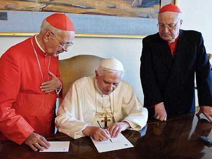 El Papa firma un documento en presencia de los cardenales Angelo Sodano (derecha) y Eduardo Martínez Somalo.