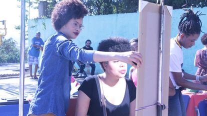 Camila Lima, responsable del taller de maquillaje organizado para el evento “Claudias, Eu? Negra!”, anima a una de las participantes a observar en el espejo la belleza que el “ser Mujer Negra” le ha brindado.
