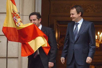 El presidente de Cantabria, Miguel Ángel Revilla, besa la bandera española junto a José Luis Rodríguez Zapatero.