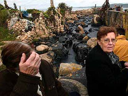 Vecinos de Camelle contemplan en el puerto de la localidad coruñesa los efectos de la mancha de fuel vertida por el petrolero <b></b><i>Prestige.</i>