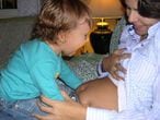 Una niña mira la barriga de su madre embarazada. EFE/Archivo