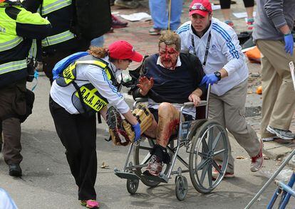 Una persona que result&oacute; herida en una explosi&oacute;n cerca de la l&iacute;nea de meta de la marat&oacute;n de Boston es evacuada del sitio en una silla de ruedas.