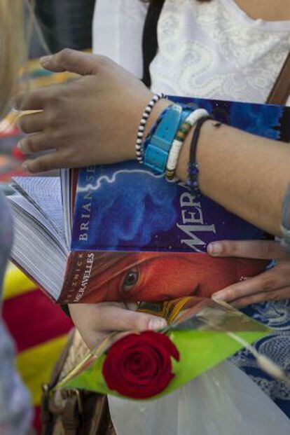 Una mujer mira un libro agarrando una rosa.