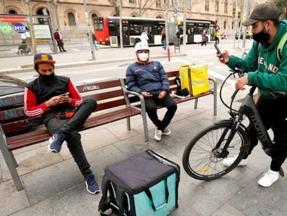 Repartidores de Glovo, Deliveroo y Uber Eats esperando algún servicio en Barcelona. 