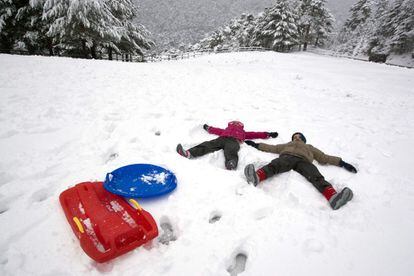 Dos ni&ntilde;os disfrutan de la primera nevada de la temporada en el puerto de Navacerrada.