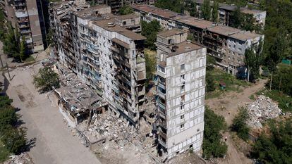 This aerial picture taken on July 13, 2022, shows destroyed buildings and residents in the yard in the city of Mariupol, amid the ongoing Russian military action in Ukraine. (Photo by Andrey BORODULIN / AFP)