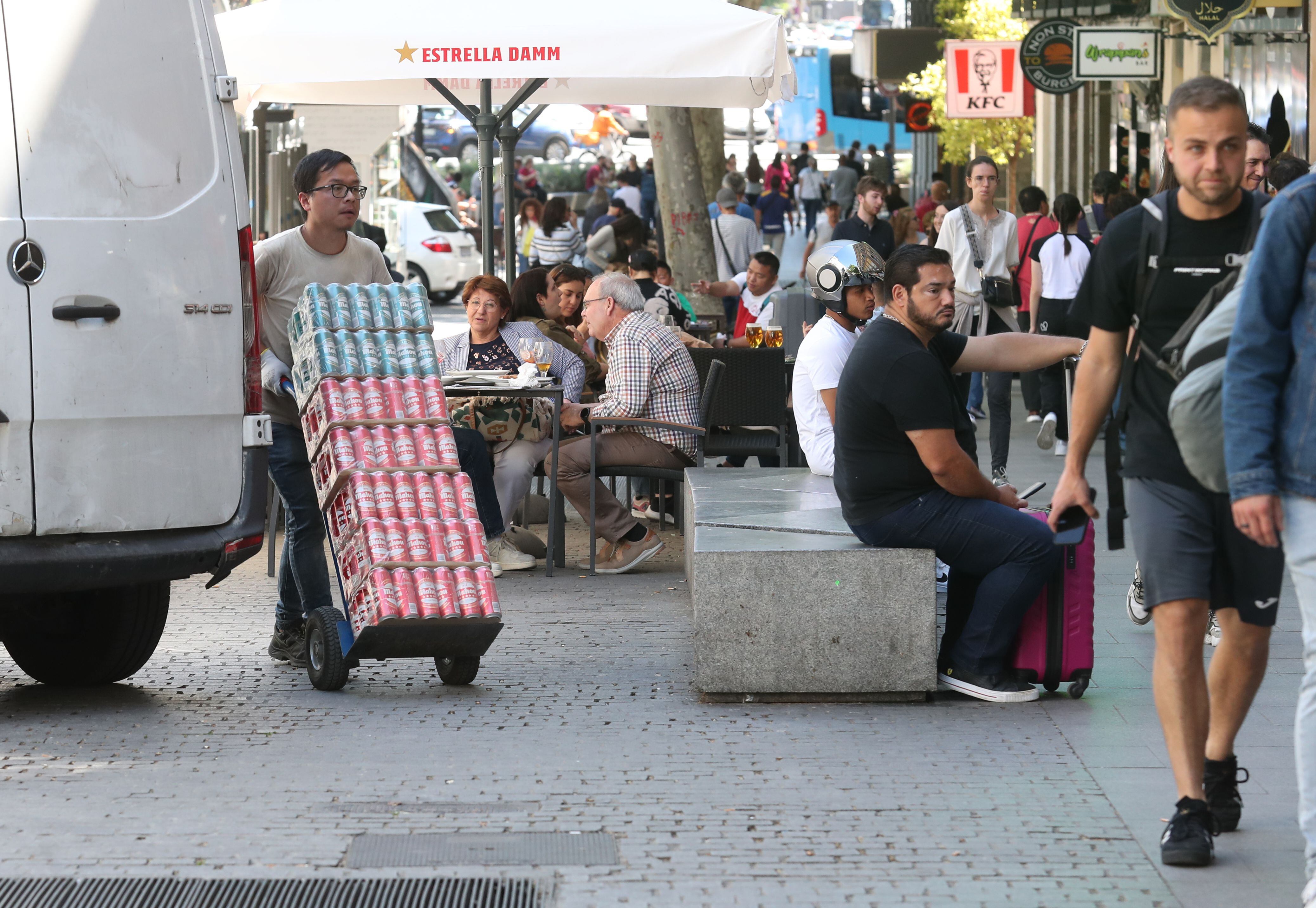 Un repartidos aparca en la acera de la calle Atocha para dejar mercancía; al fondo, terrazas de varios locales. 