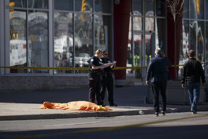 Policías junto a un cuerpo cubierto en la acera donde una camioneta ha atropellado a numerosos peatones en Toronto.