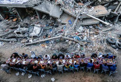 Familias palestinas se sientan a la mesa tras una jornada de ayuno en la  franja de Gaza durante el Ramadán, en mayo. El edificio a su lado fue destrozado durante los enfrentamientos entre la milicia palestina Hamás e  Israel durante la disputade Gaza, una lengua de tierra habitada por 1,8  millones de personas.