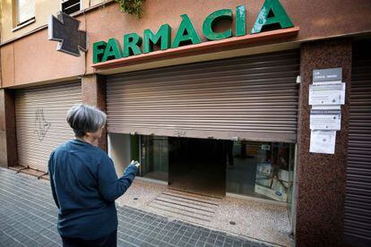 Una empleada de la farmacia de la calle Guardiola i Feliu baja la persiana esta mañana.