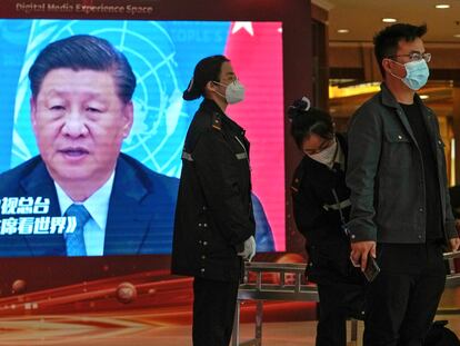 Personal de seguridad cachea a un periodista junto a una pantalla que muestra imágenes del presidente de China, Xi Jinping, en un hotel dedicado a los medios en Pekín, este viernes.