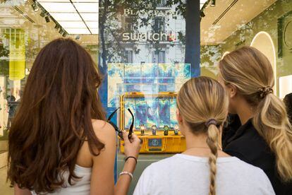 Tres clientas observan los relojes de Blancpain x Swatch expuestos en el escaparate de la 'boutique' de Swatch de la calle Serrano, en Madrid.