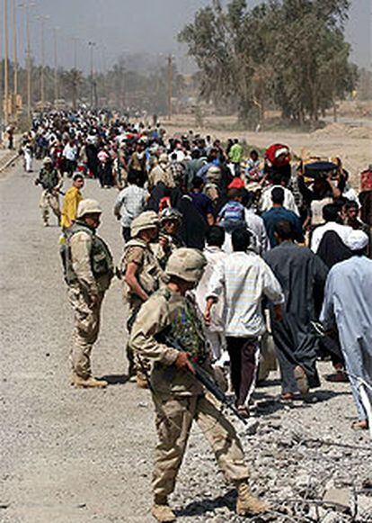 Varios <i>marines</i> observan cómo una columna de iraquíes huye a pie de la anarquía de Bagdad.