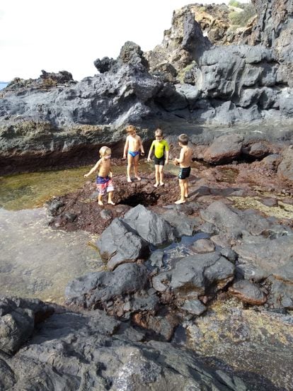 Varios alumnos de la Playa Escuela El Médano observan los agujeros de la playa y se preparan para lanzar piedras a un agujero.
