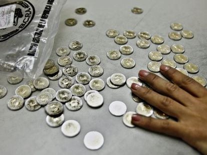 Una empleada cuenta monedas en una taquilla de tren, en Buenos Aires.