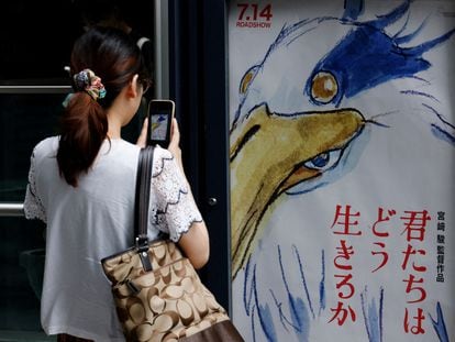 Una mujer toma una fotografía del póster de la nueva película de Miyazaki en un cine en Tokio el 14 de julio de 2023.