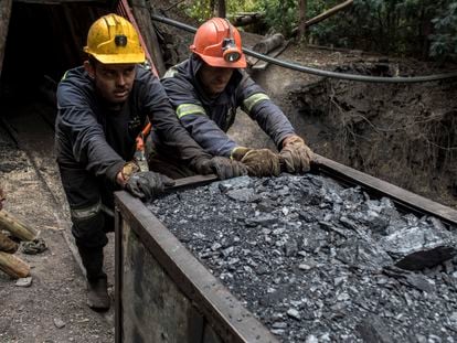 Dos mineros empujan un vagón de carbón fuera de una mina en Cucunuba, Colombia.