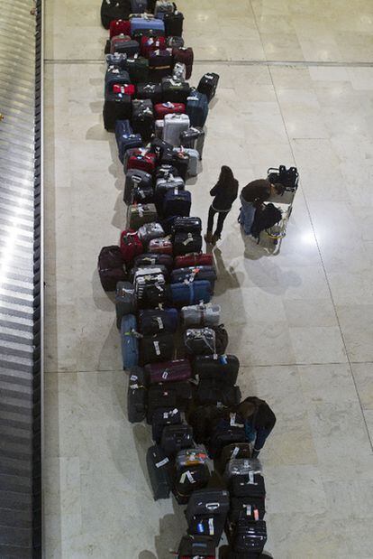 Una viajera mira las maletas acumuladas en una fila, ayer en el aeropuerto de Barajas.
