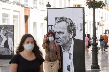 Una mujer posa junto a un cartel de José Coronado en la exposición 'Cine de cerca' en la calle Marqués de Larios, en Málaga.