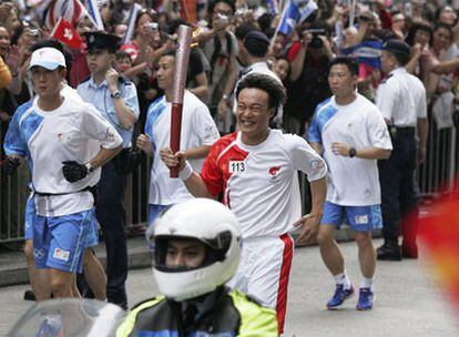 Un sortiente relevista porta la antorcha olímpica por las calles de Hong Kong.