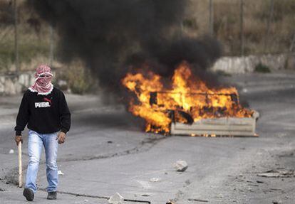 Un joven palestino camina junto a un sofá en llamas en los disturbios en el barrio de Issawiya, en Jerusalén Este, durante la celebración de la 63ª Nakba.