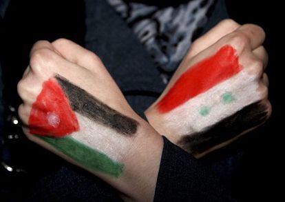 Un sirio se manifiesta en Amm&aacute;n con las banderas de Jordania (izquierda) y Siria pintadas en las manos.