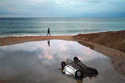 Uno de los coches que fueron arrastrados hasta la playa de Calella quedó volcado.
