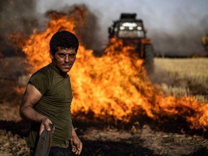 Un grupo de personas combate un incendio en un campo agrícola en la villa de al-Qahtaniyah, cerca de la frontera entre Siria y Turquía.