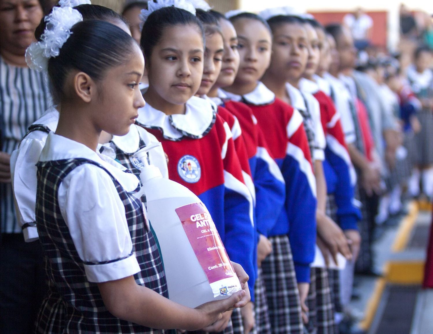 Una niña sostiene un bote de gel antibacterial en una escuela de Nuevo León, México.