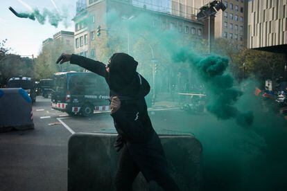 Un manifestante lanza un bote de humo contra la policia, durante los altercados de los CDR en Barcelona. 