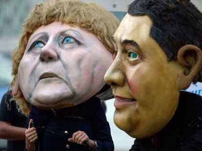 Protesta contra la injusticia social con máscaras Merkel y Sigmar Gabriel, del SPD, en la segunda ronda de negociaciones en Berlín.