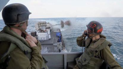 Captura de vídeo donde se muestra a dos soldados israelíes observando cómo un buque militar israelí dispara sobre una posición sin determinar en la franja de Gaza, este domingo. 
