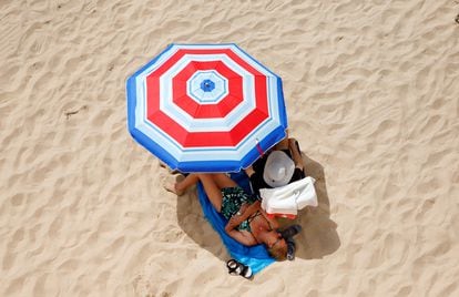 Dos turistas disfrutan del sol y el mar en la playa de Levante de Benidorm, este viernes.