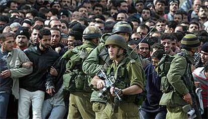 Soldados israelíes vigilaban ayer a decenas de trabajadores palestinos, que fueron detenidos antes de devolverlos a Gaza.