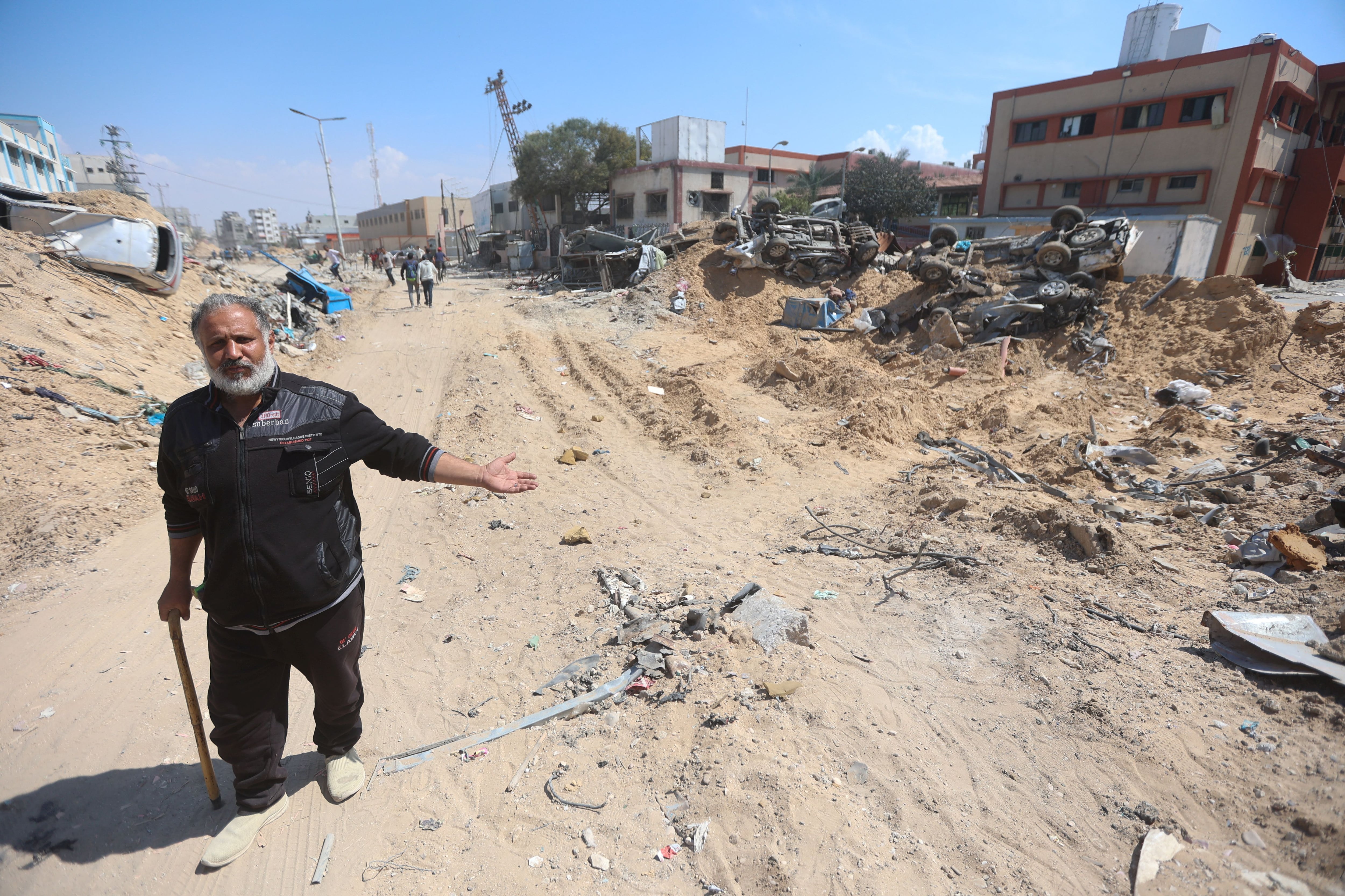 Un hombre señala una calle llena de escombros y los edificios destruidos que la flanquean, este domingo en Jan Yunis, al sur de la franja de Gaza.