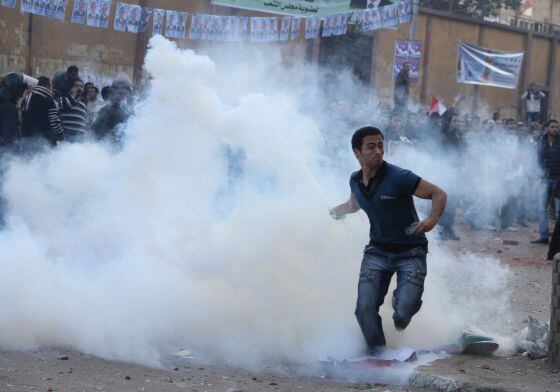 Un hombre arroja un bote de gas lacrimógeno a la policía.