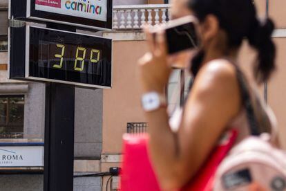 Una mujer pasa en Mallorca junto a un termómetro que muestra la temperatura en grados Celsius, el pasado agosto.