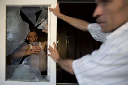 Un palestino retira los cristales rotos de una ventana en una calle de Gaza, tras un ataque aéreo, el 10 de julio de 2014.