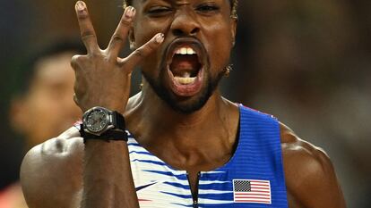 Noah Lyles, sin cadena al cuello, muestra tres dedos, por sus tres oros, tras ganar el relevo.