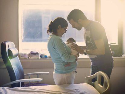 Dos padres miran a su recién nacido.