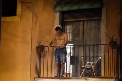 Un hombre se asoma al balcón en el barrio de El Raval, en Barcelona, durante una de las tórridas noches de agosto. 