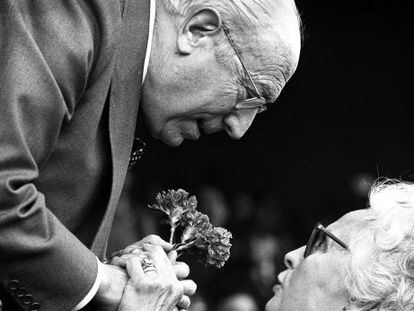 Enrique Tierno Galv&aacute;n, recibe un ramo de claveles de manos de una mujer, durante un acto en 1981
    