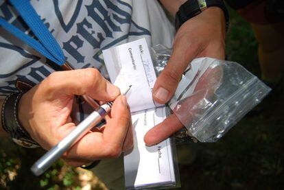 Una aficionada al 'geocahing' firma en el libro de visitas de un tesoro.