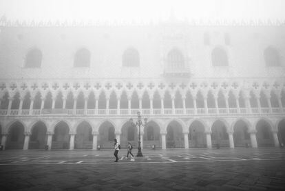 Unos turistas caminan frente al Palacio Ducal, en la Plaza de San Marcos, bajo la espesa niebla.