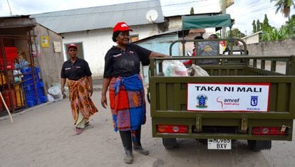 Dos mujeres de Taka Ni Mali depositan la basura en el carromato para su traslado.