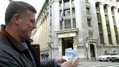 Un ciudadano muestra unos billetes de euro retirados de un cajero autom&aacute;tico.
