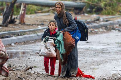 Una mujer y una niña palestinas caminan entre el barro, mientras abandonan el norte de Gaza para desplazarse hacia el sur, durante la tregua acordada entre Israel y Hamás, este lunes.