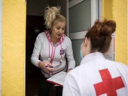 Cristina, voluntaria de Cruz Roja, reparte un lote a Yoslen Garrido, en el barrio de Nou Barris.