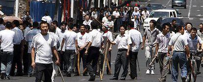 Un grupo de hanes (etnia mayoritaria de China) armado con palos y piedras pretenden agredir a los miembros de la minoría uigur a los que acusan de la destrucción de sus comercios.