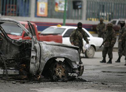 Militares inspeccionan un vehículo calcinado en la zona donde se produjo el combate con los sicarios.